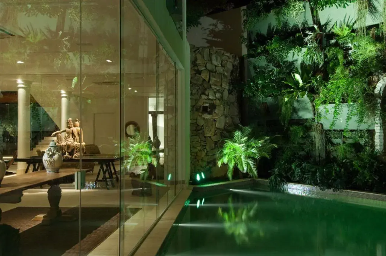 A iluminação noturna realça o azulejo de piscina verde. Projeto de Di Pace e Di Pace Arquitetura e Interiores