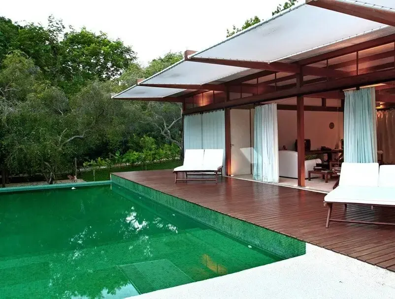 A piscina verde e o deck de madeira se destacam nessa área externa. Fonte: Blog Sincenet