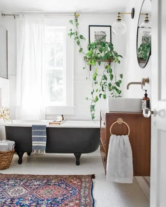 Banheira de pé cinza chumbo no banheiro moderno decorado com plantas e gabinete de madeira