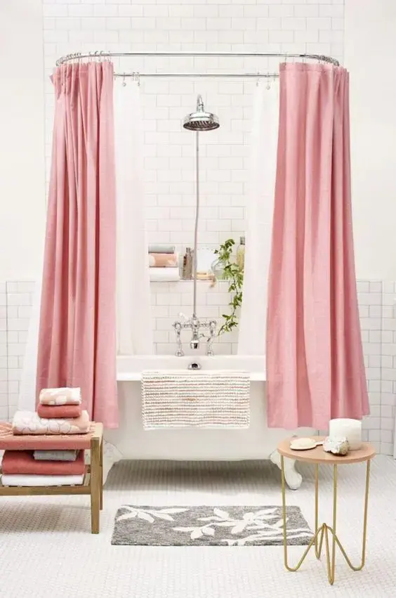 Banheiro branco com banheira de pé e cortina rosa