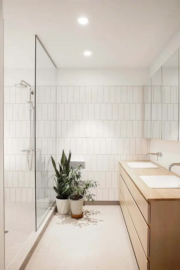 Banheiro com gabinete de madeira e revestimento cerâmico branco. Fonte: HomeDeco