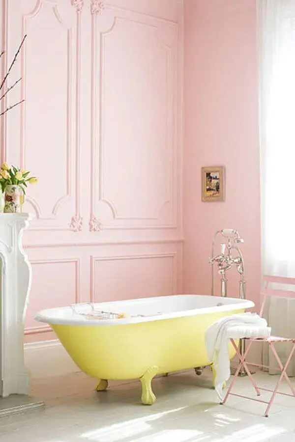 Banheiro rosa com banheira de pé amarela