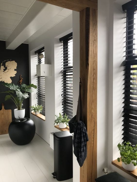 Casa com persiana preta horizontal e vasos de plantas decorando o corredor