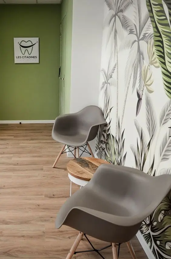 Consultório dentário com sala de espera decorada com papel de parede de plantas e cadeira cinza