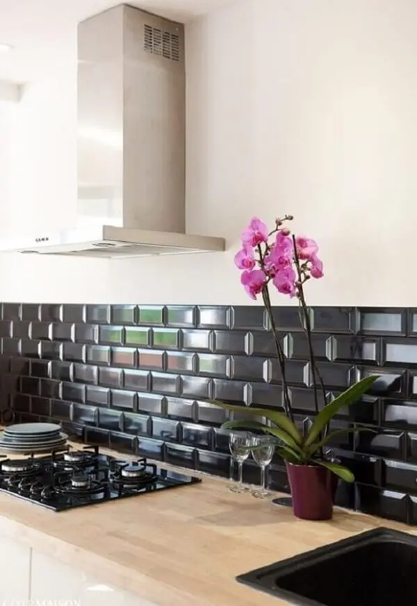 Cozinha rústica com bancada de madeira e revestimento cerâmico preto na parede. Fonte: Duas Arquitetura