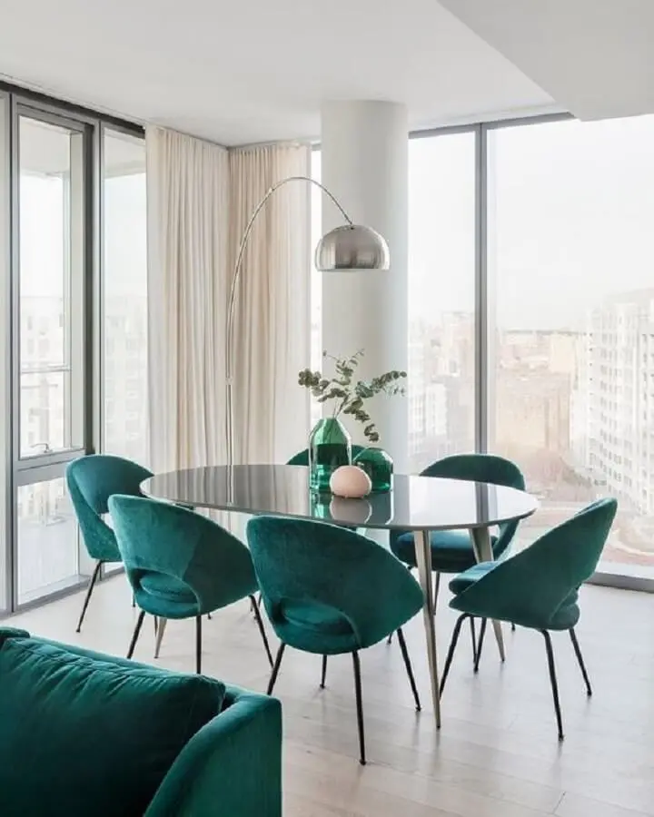 Decoração clean para sala de jantar com mesa oval preta e cadeira estofada verde Foto Curated Interior