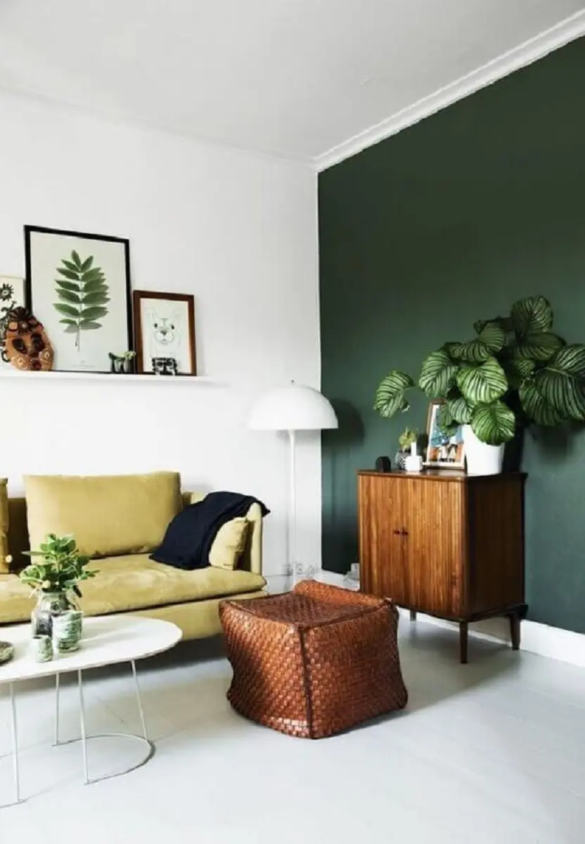 Decoração de sala de estar com parede verde e armário de madeira pequeno