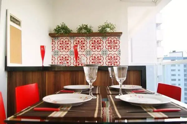 O revestimento cerâmico com nuances em vermelho se conecta com as cadeiras da mesa. Projeto de Priscila Fernandes Arquitetura