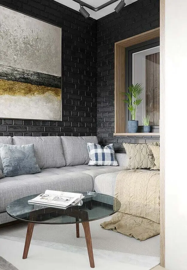 O sofá cinza se contrasta com o revestimento cerâmico tijolinho preto da parede. Fonte: Raquel Sousa