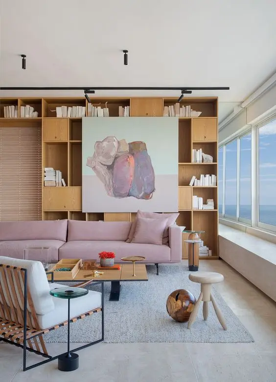 Sala com estante de livros e sofá rosa