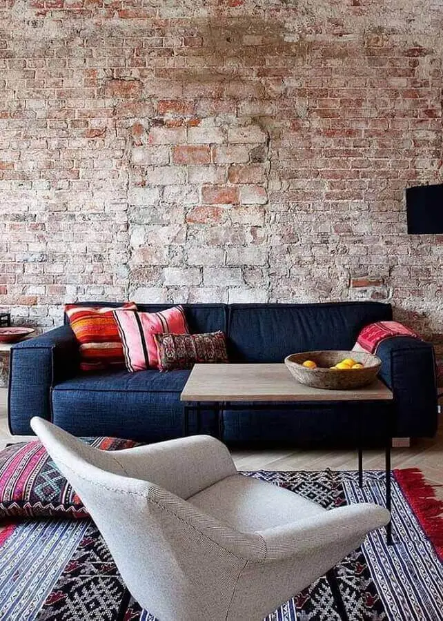 Sala com parede de tijolinho rustico e sofá azul marinho