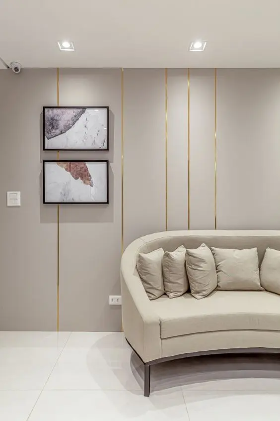 Sala de espera chique com sofá redondo bege e papel de parede dourado 