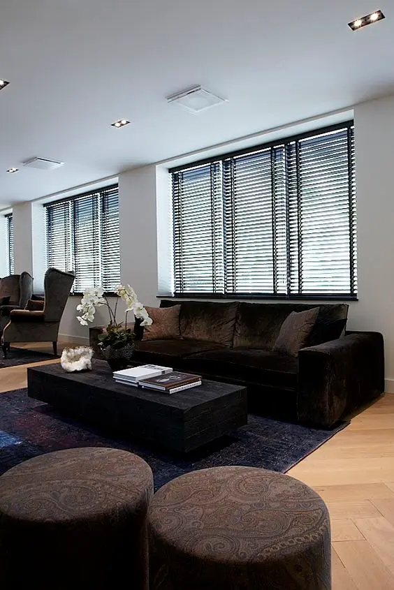 Sala de estar com sofá marrom e persiana preta