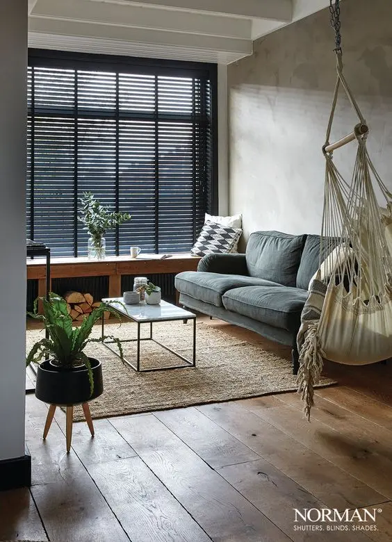 Sala de estar pequena com persiana preta e sofá cinza