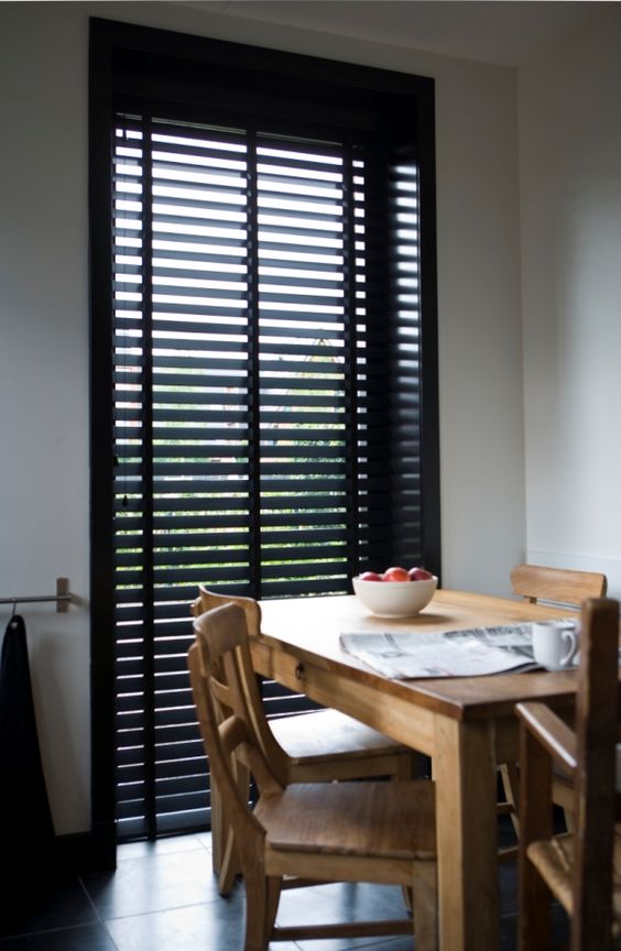 Sala de jantar com mesa de madeira e persiana preta
