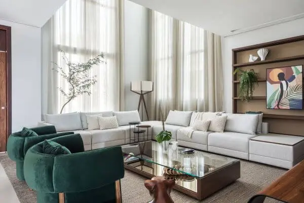 Sala grande decorada com poltronas verdes e sofás bege