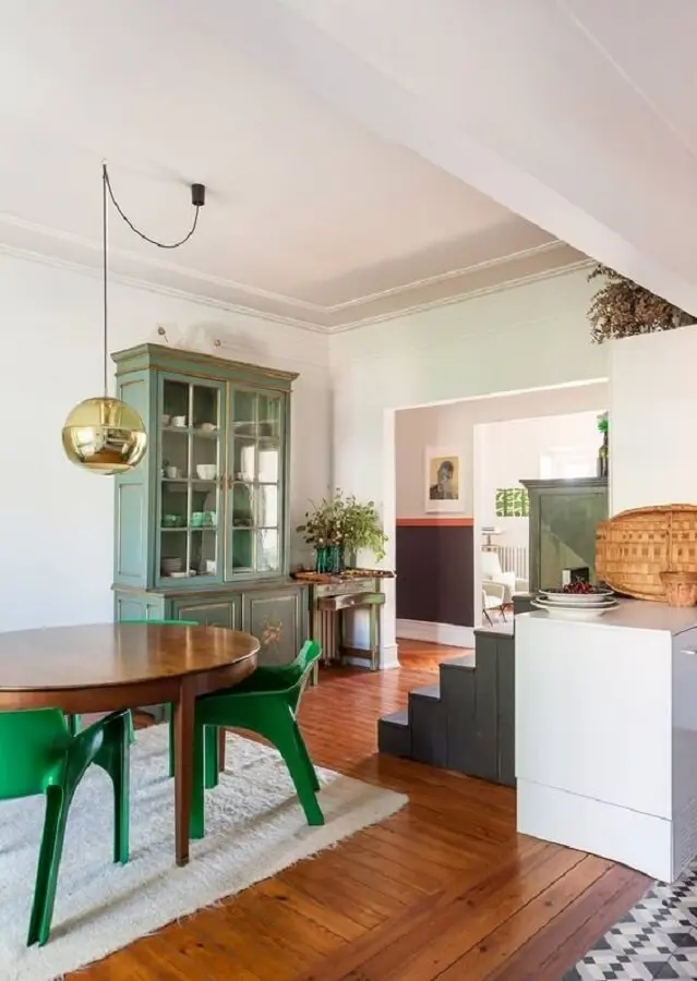 cadeira verde moderna para sala de jantar decorada com mesa de madeira e luminária redonda  Foto Histórias de Casa