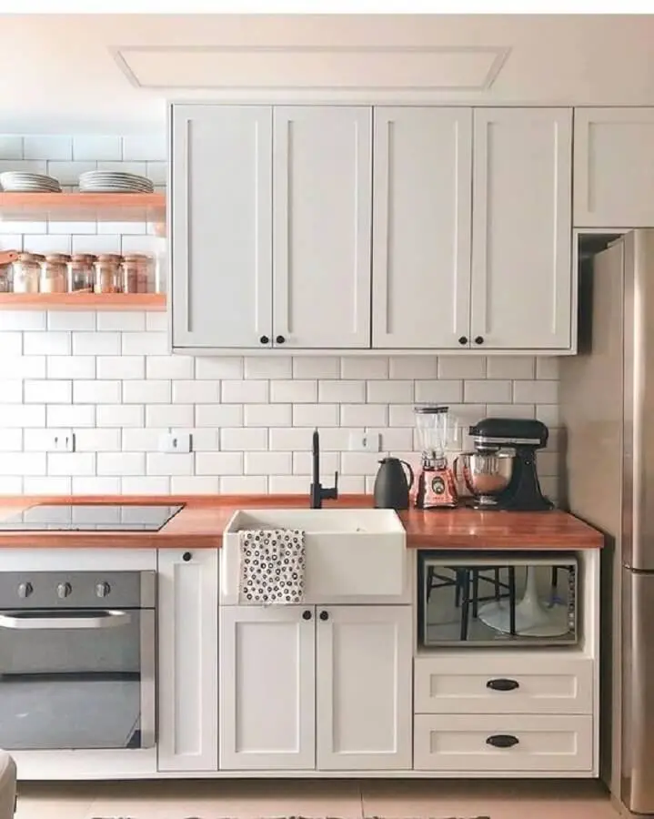 Cozinha branca decorada com armário vintage bancada de madeira e azulejo de cozinha branco simples