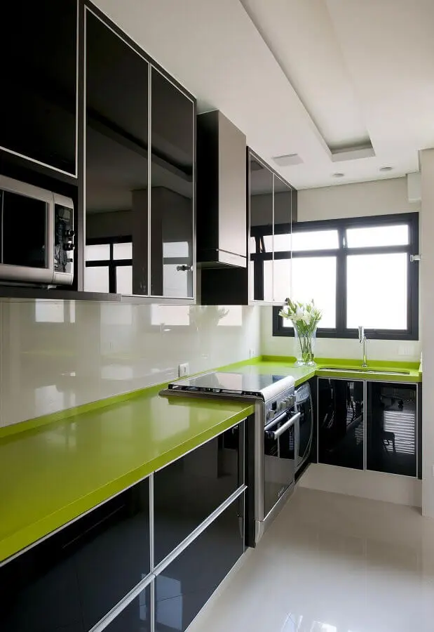 Cozinha preta e branca decorada com bancada na cor verde limão