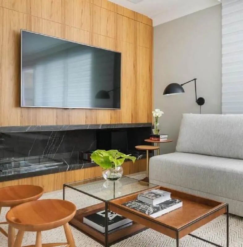 sala com lareira grande decorada com sofá cinza sem braço e revestimento de madeira Foto Pinterest