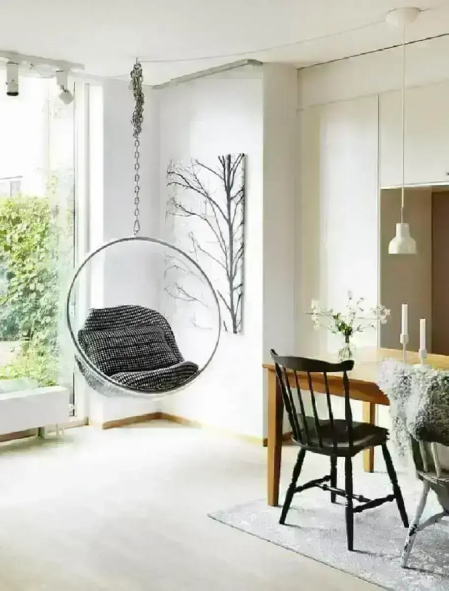 Sala de jantar branca decorada com cadeira de balanço moderna suspensa Foto Sundry Society