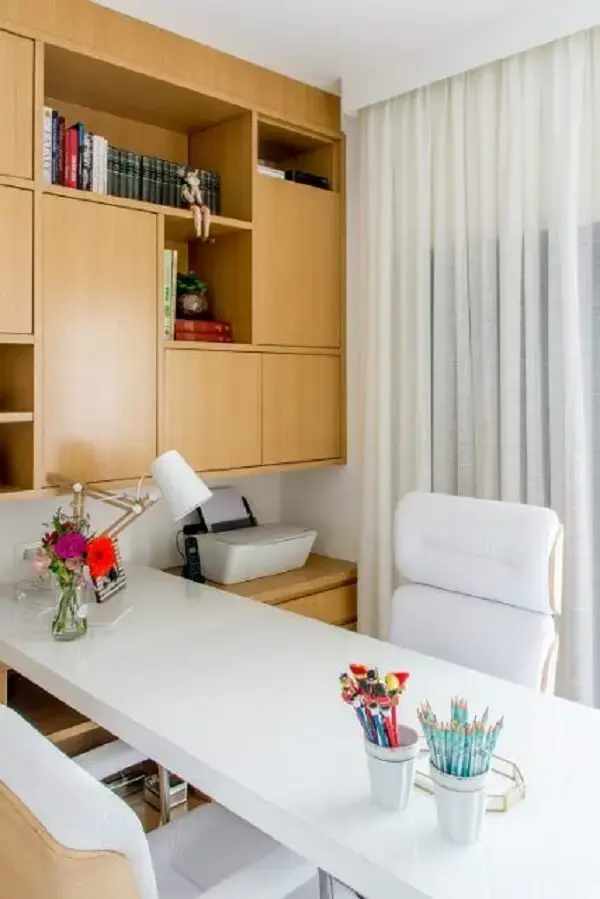 A cortina branca barra parcialmente a entrada de luz natural no escritório pequeno. Projeto de Lu Boschi Designer de Interiores