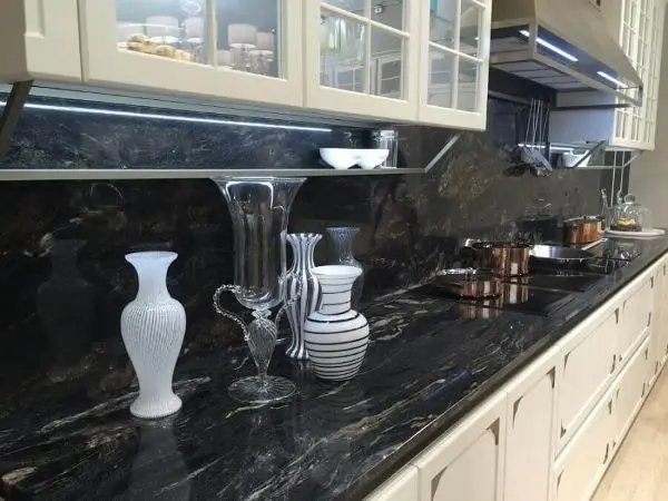 Bancada de mármore na cozinha moderna com armários brancos e vasos de vidro