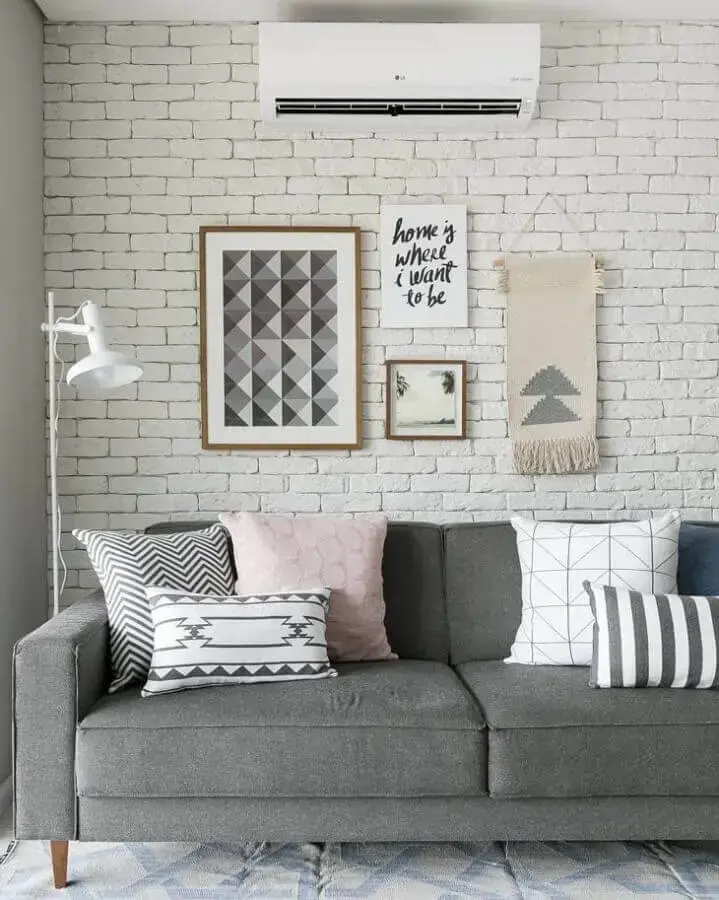 Combinação de almofadas para sofá cinza em sala decorada com parede tijolinho branco Foto Gisele Rampazzo
