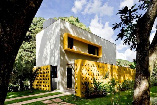 Cores para fachadas de casas com cobogó amarelo e tinta cinza