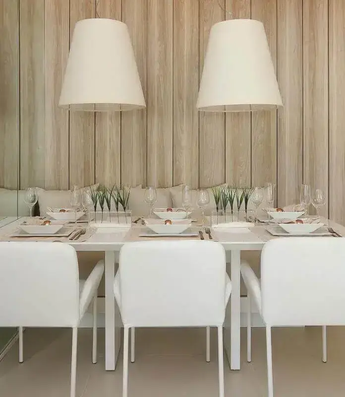 Cores para sala de jantar pequena decorada com luminária branca e revestimento de madeira para parede  Foto Mariana Orsi