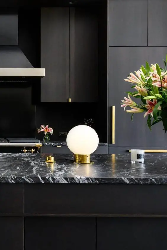 Cozinha com bancada de mármore preto e vaso de flores