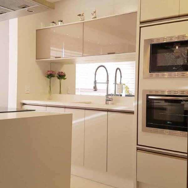 Cozinha com bancada de quartzo branco e armários da mesma cor