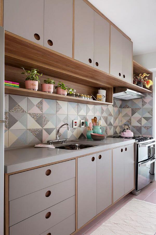 Cozinha moderna com bancada de quartzo cinza e revestimento geométrico na parede