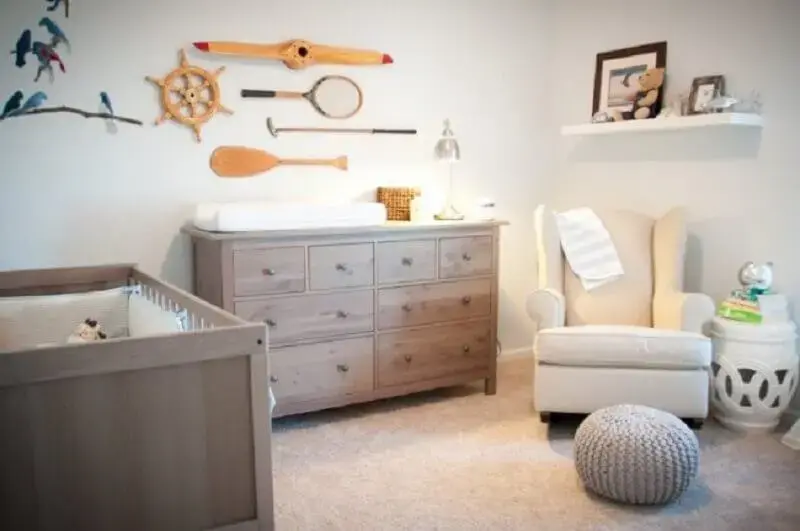 Cômoda de madeira maciça para quarto de bebê decorado com puff de crochê e poltrona de balanço Foto Happy Modern