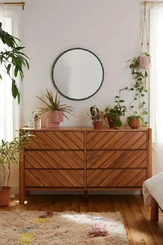 Cômoda de madeira para quarto decorado com vasos de plantas e espelho redondo  Foto Urban Outfitters