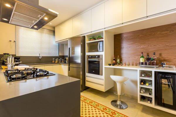 Decoração de cozinha em u com bancada de quartzo marrom e móveis planejados