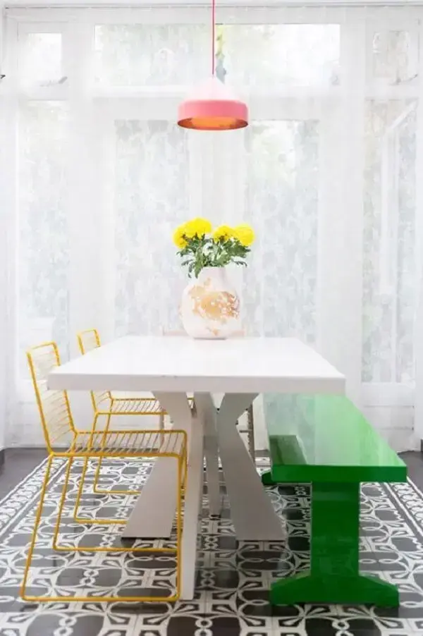 Decoração com mesa de jantar retangular branca cadeiras amarela e banco verde