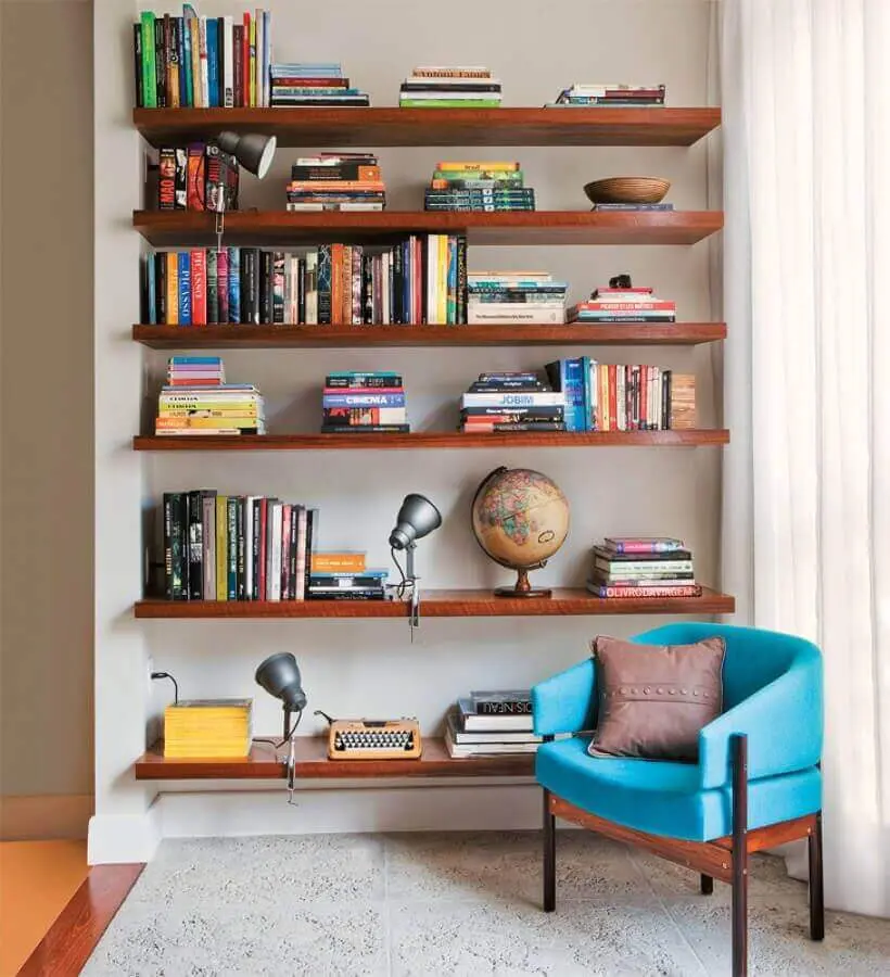 Decoração com prateleiras de madeira para livros e poltrona confortável para leitura Foto Jeito de Casa