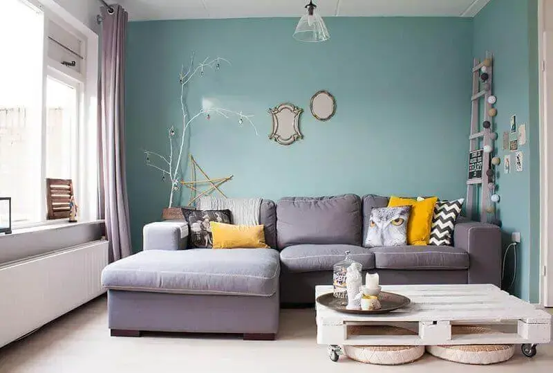 Decoração de sala com parede azul e almofadas para sofá cinza Foto Kyle Bunting