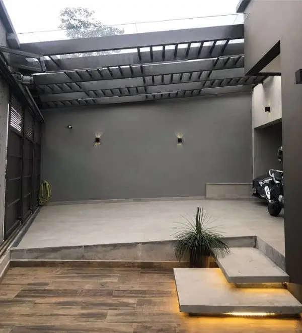 Garagem moderna com cerâmica bege e piso amadeirado na entrada de casa 