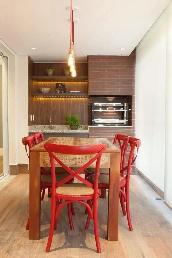 Lustre pendente para área gourmet decorada com cadeiras vermelhas para mesa de madeira rústica Foto Liliana Zenaro
