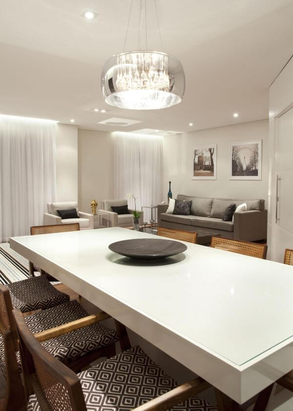 Mesa de jantar branca com cadeiras cinza e lustre espelhado