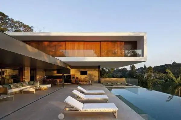 Móveis para piscina com espreguiçadeira branca e sofás na varanda