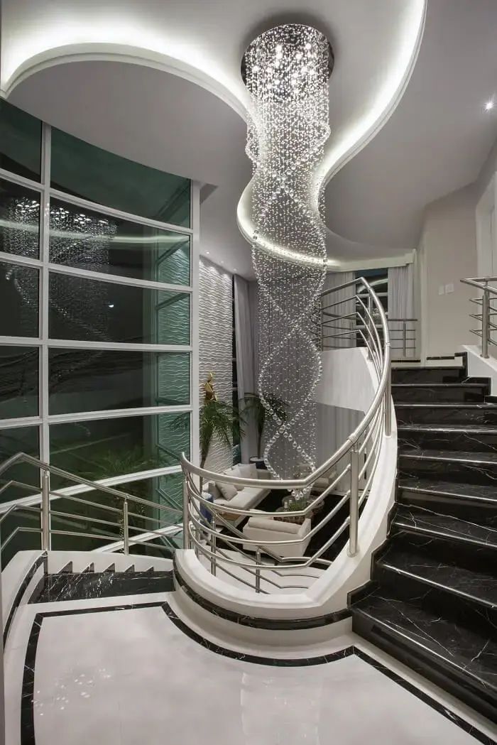 O lustre comprido para escada se destaca na decoração do ambiente. Projeto de Aquiles Nicolas Kílaris