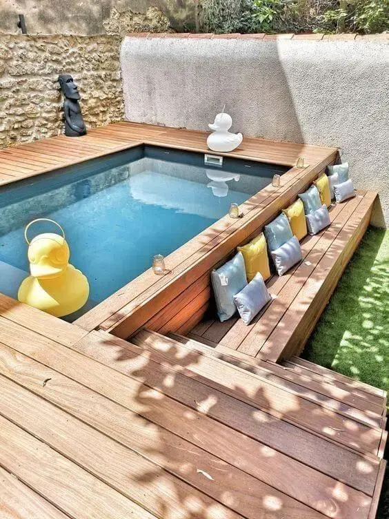 Piscinas modernas com deck de madeira e almofadas coloridas para deixar o ambiente mais confortável