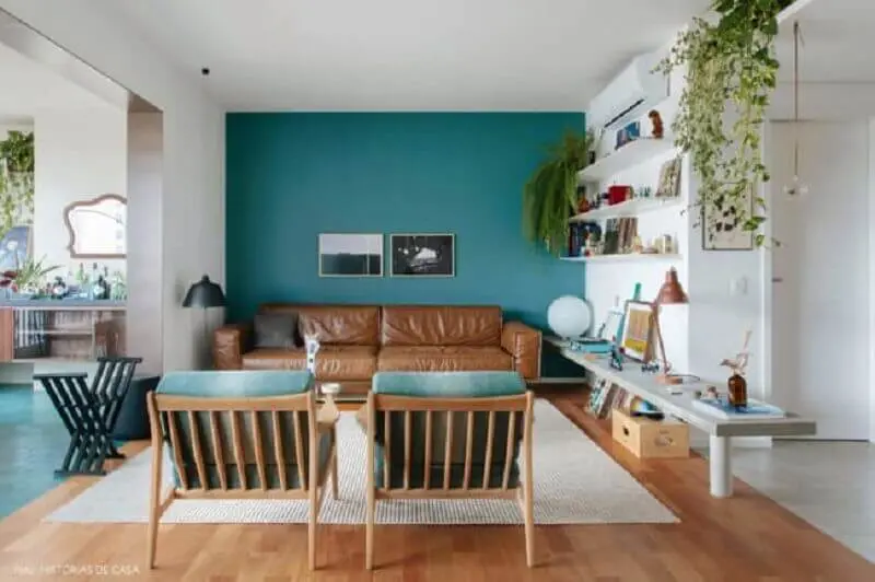 Sala azul e branca decorada com sofá cor caramelo e poltrona de madeira Foto Jeito de Casa