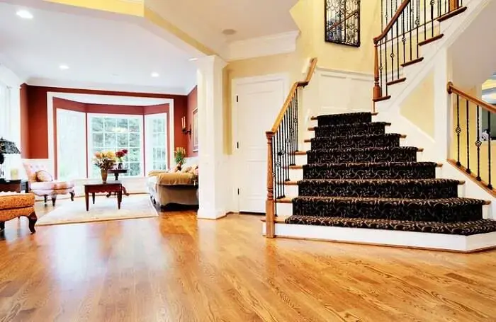 Sala com carpete de madeira e proteção de feltro nas escadas