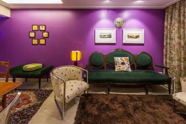 Sala com parede roxa e móveis vintage verde e madeira