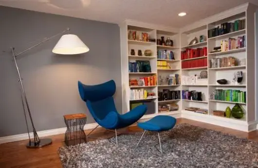 Sala de estar com estante de canto e poltrona azul