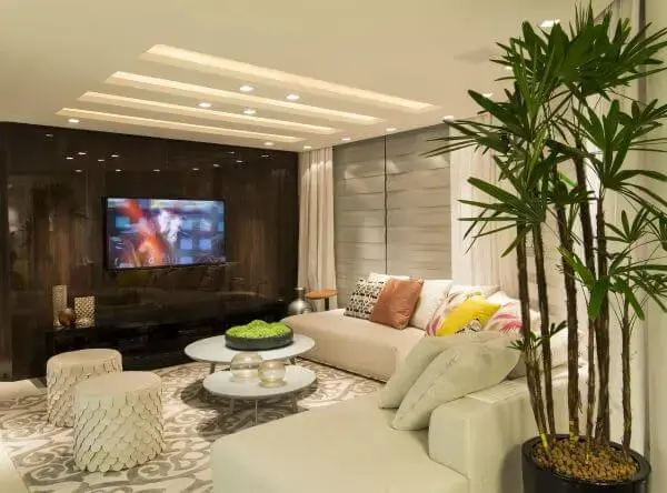 Sala de tv com sofá redondo e almofadas grandes coloridas